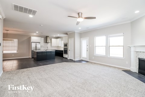 A spacious living room with a fireplace and a ceiling fan.