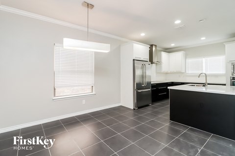 A modern kitchen with a stainless steel refrigerator and black countertops.