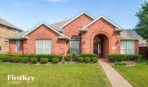 the front of a brick house with a lawn and a walkway