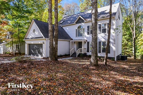 a white house in the woods with trees