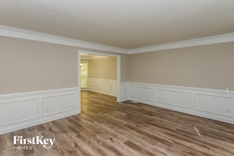 the living room of a house with wooden floors and white walls