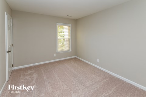 a bedroom with a carpeted floor and a window