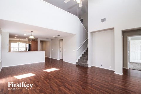 A spacious living room with wood flooring and a staircase leading to another level.
