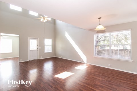 A room with wooden floors and a large window with blinds.