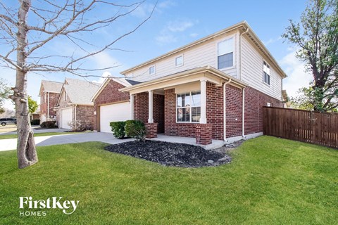 A brick house with a white trim and a small front yard.