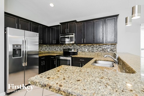 a kitchen with granite counter tops and black cabinets