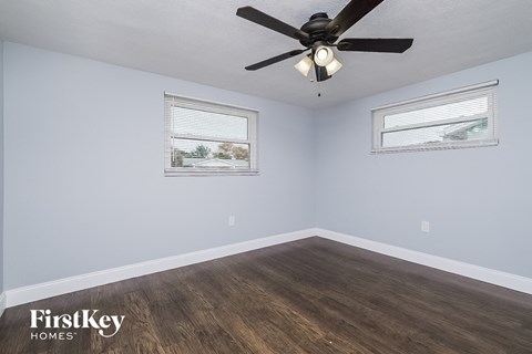 the bedroom has a ceiling fan and hardwood floors