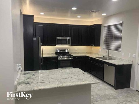 an empty kitchen with black cabinets and marble counter tops