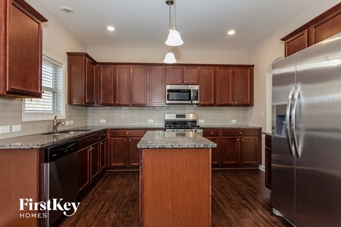 A kitchen with wooden cabinets and a stainless steel refrigerator.