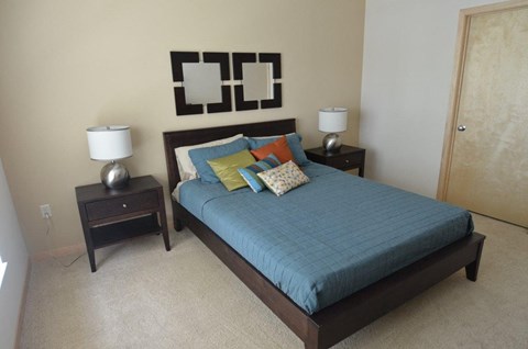 A bed with a blue comforter and a lamp on a side table.