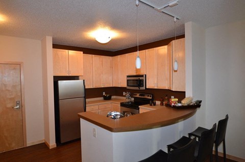 a kitchen with a bar and a stainless steel refrigerator