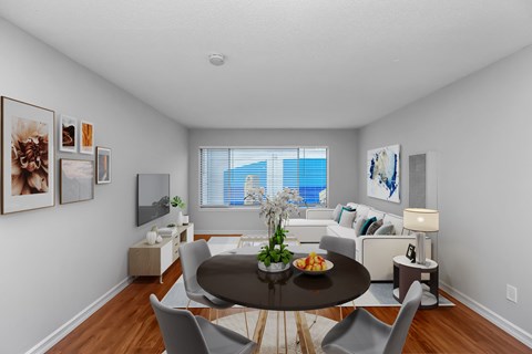 A dining room with a table set for two and a couch with pillows.