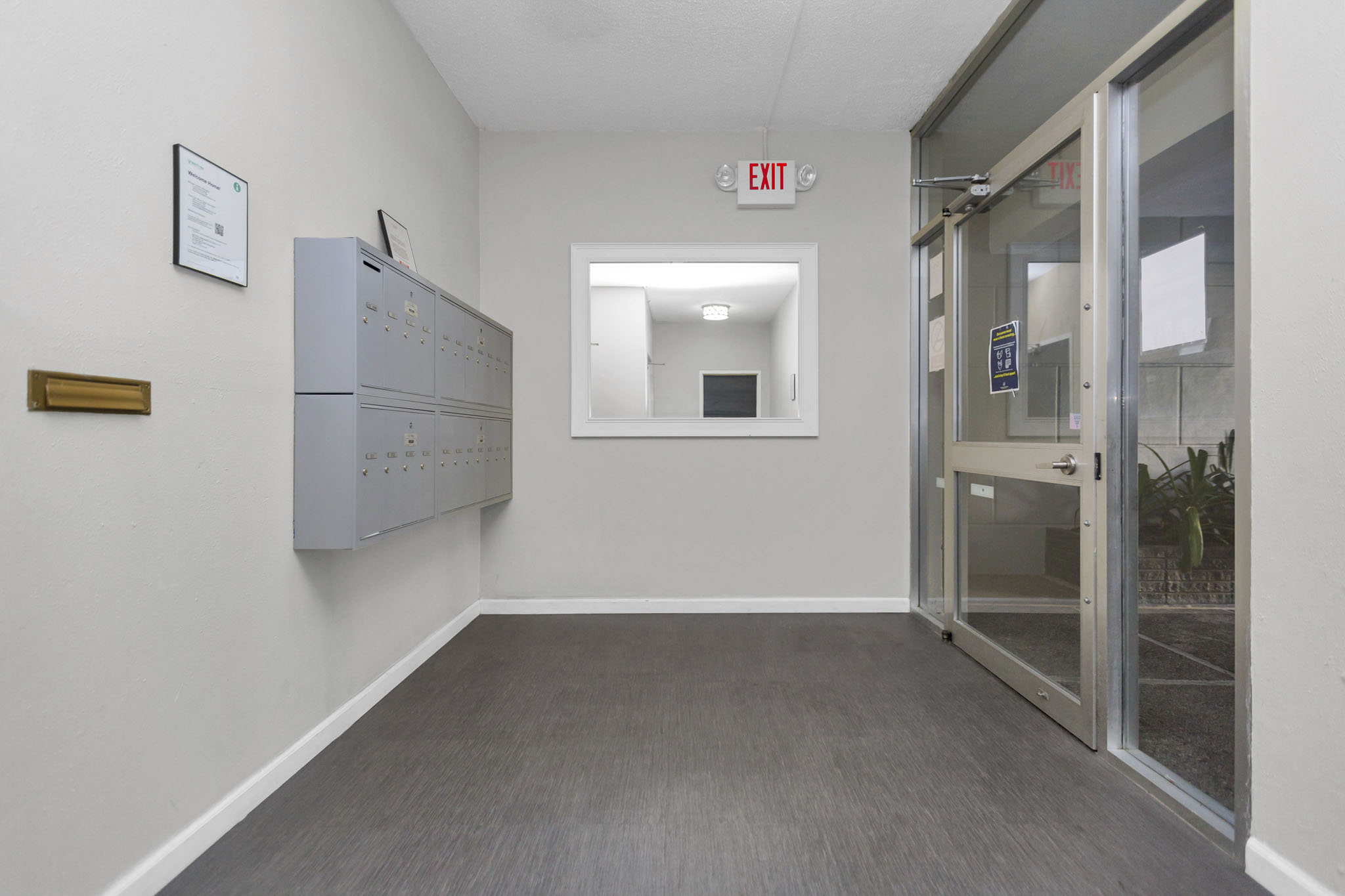 A white wall with a red exit sign on it.
