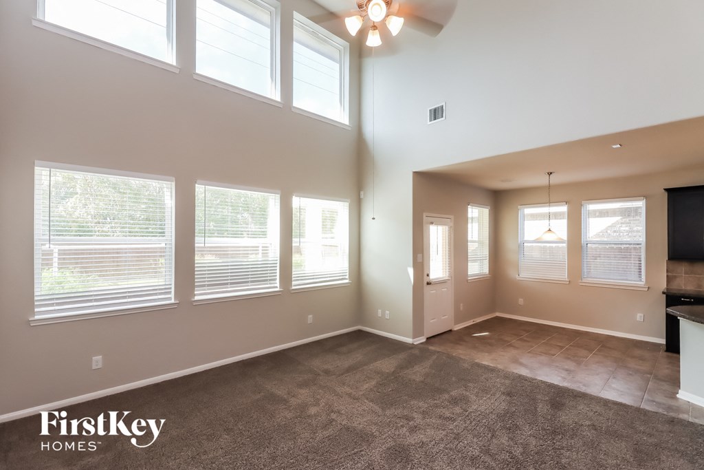 an empty living room with windows and a ceiling fan