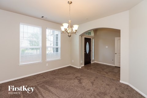 the living room and dining room of a house with carpet and a chandelier