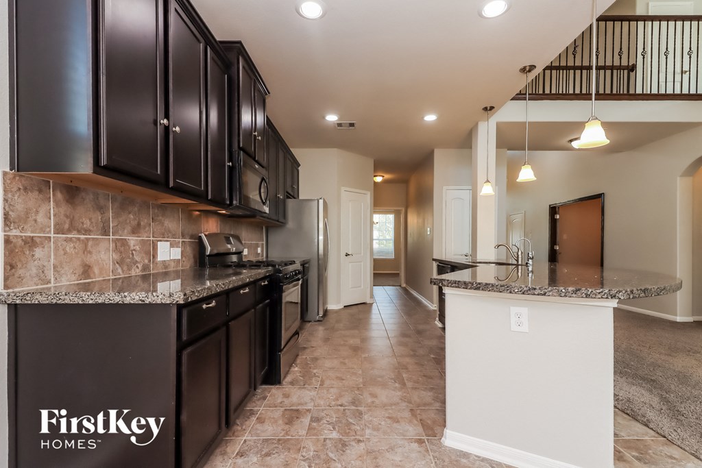 a kitchen with black cabinets and granite counter tops and a sink