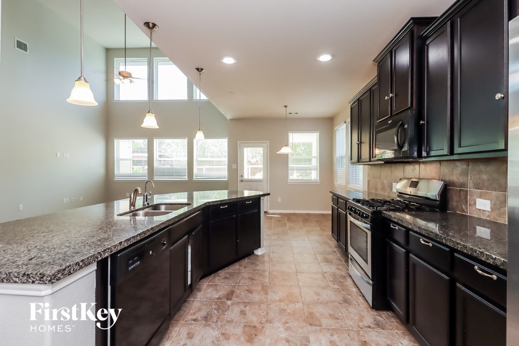a kitchen with black cabinets and granite counter tops and a sink