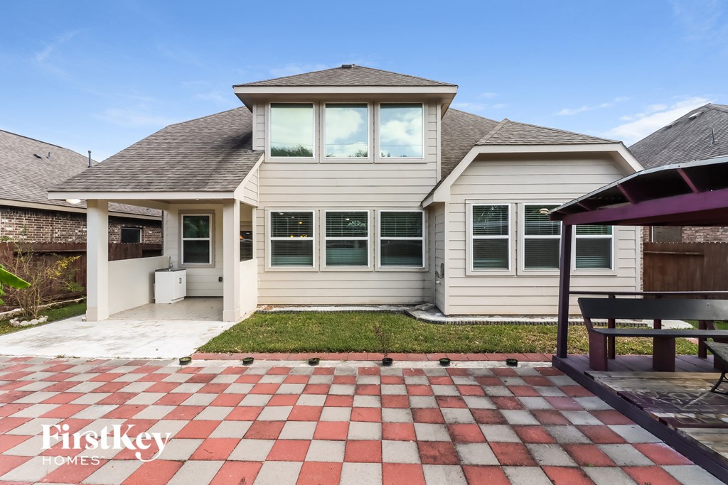 a backyard with a checkered tile patio and a house