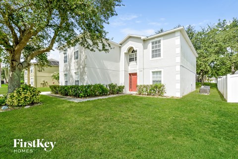 a white house with a red door and a lawn