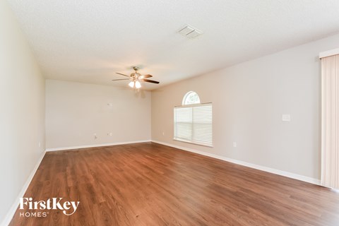 a spacious living room with hardwood floors and a ceiling fan