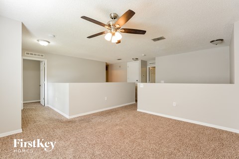 a spacious living room with carpet and a ceiling fan
