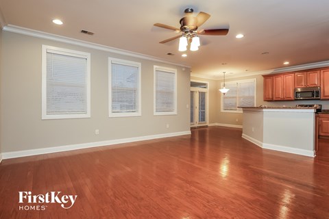 A spacious room with wooden floors and a ceiling fan.