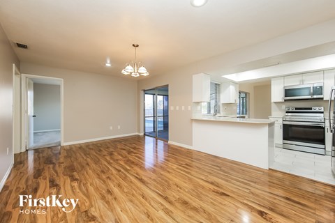A spacious kitchen and living room with wooden floors and white walls.