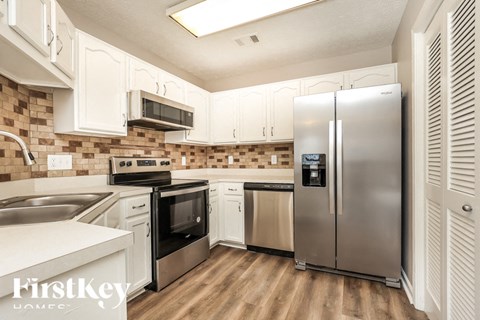 A kitchen with a stainless steel refrigerator and white cabinets.
