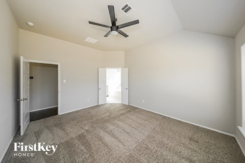 a spacious living room with carpet and a ceiling fan