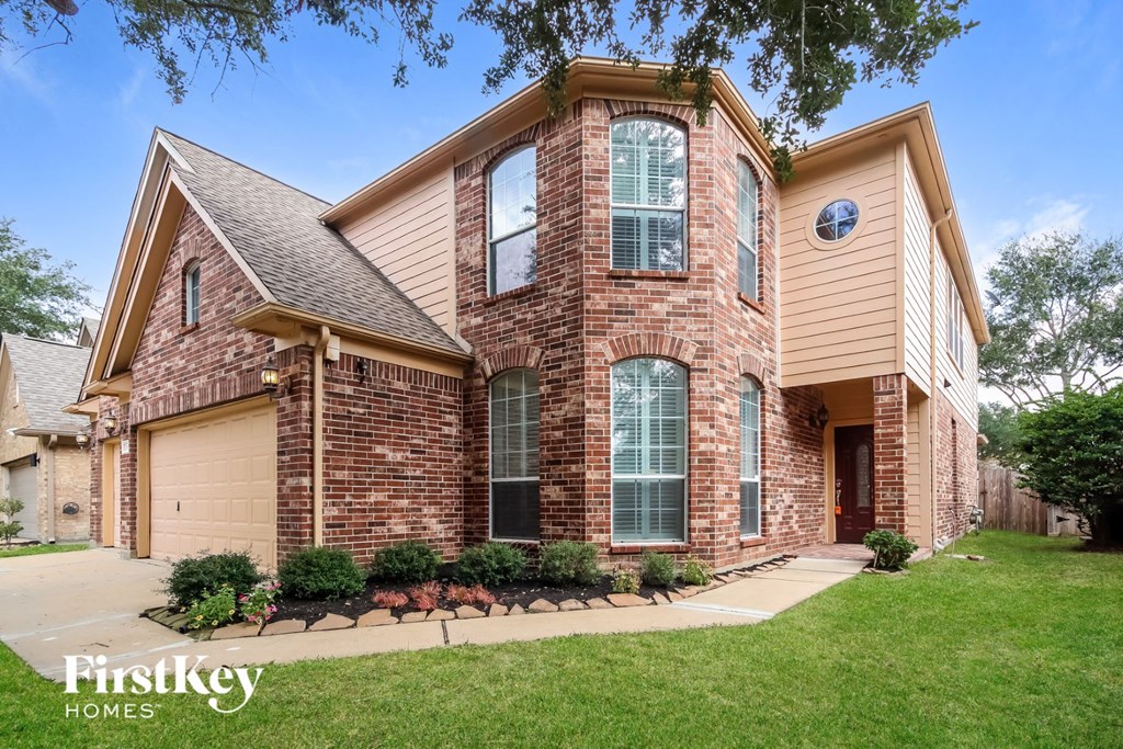 a brick house with a garage and a lawn