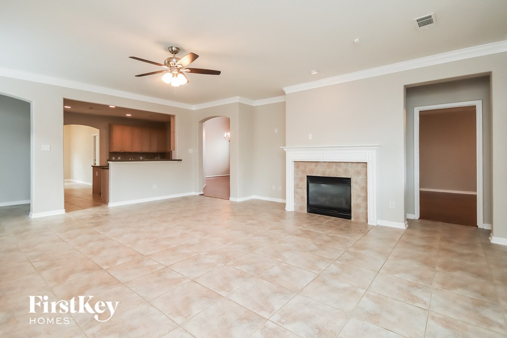 an empty living room with a fireplace and tile flooring