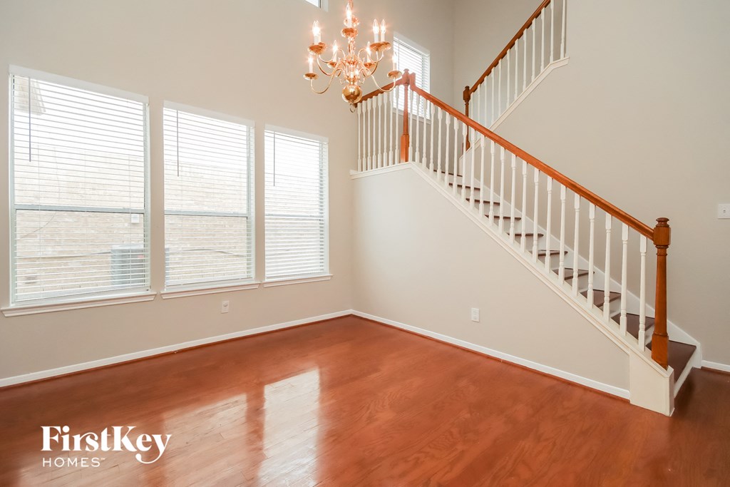 a living room with a staircase and a large window with a chandelier