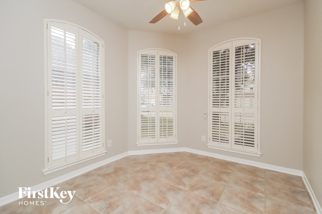 a dining room with white plantation shutters and a ceiling fan