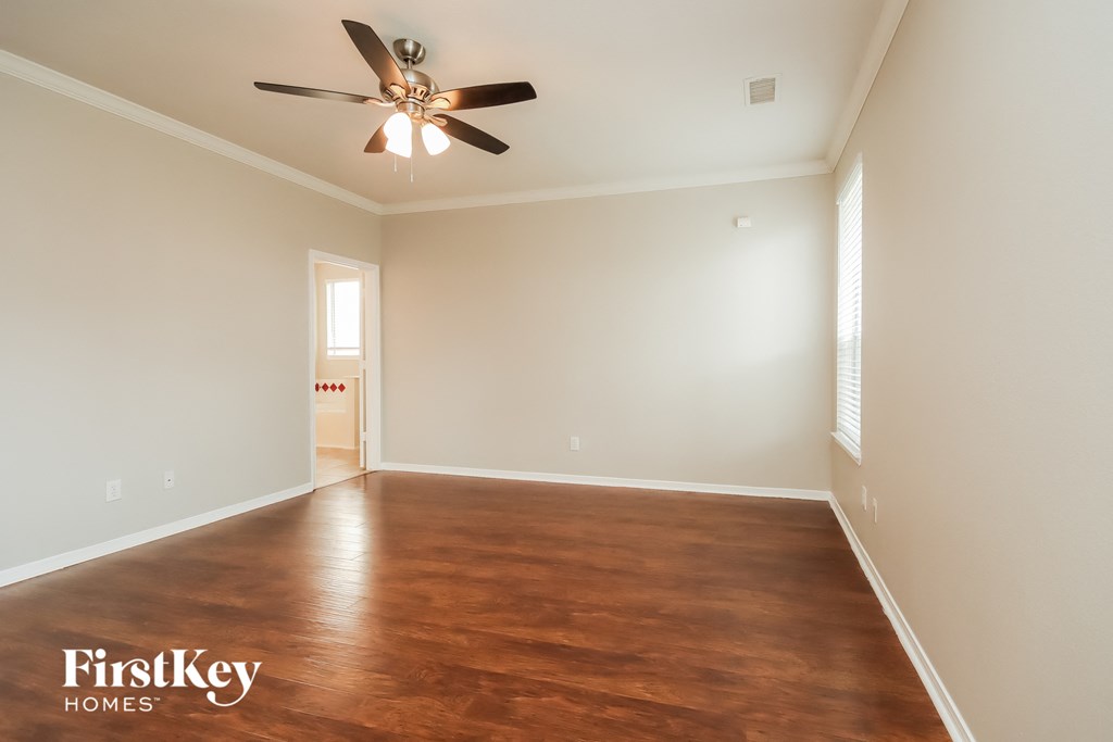 a empty living room with wood floors and a ceiling fan