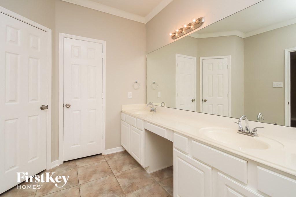 a bathroom with white cabinets and a sink and a mirror