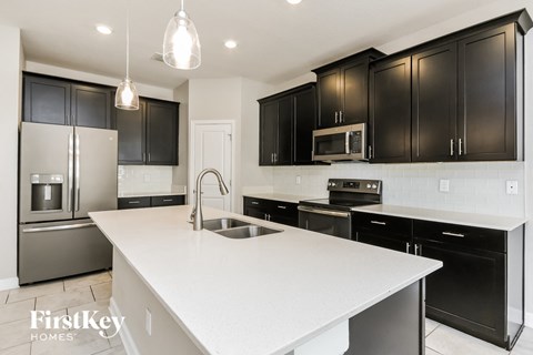 a large white kitchen with black cabinets and stainless steel appliances