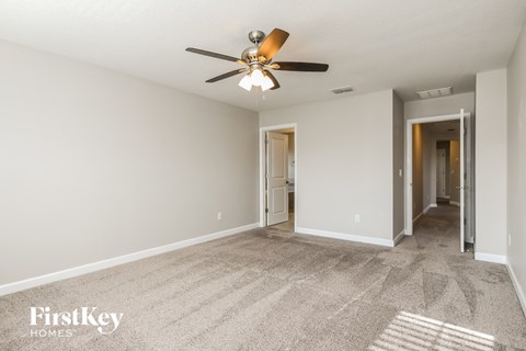 a spacious living room with carpet and a ceiling fan