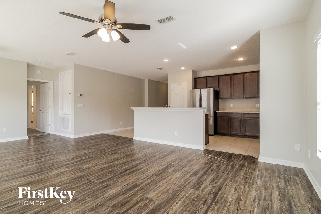 A spacious room with wooden flooring and a ceiling fan.