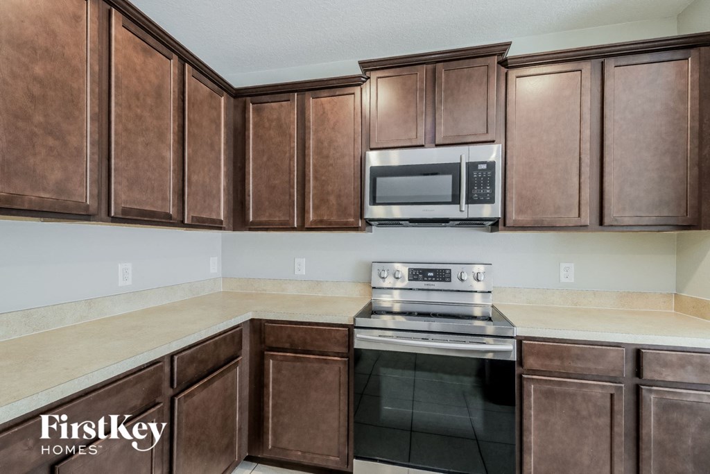 A kitchen with brown cabinets and a stove top oven.