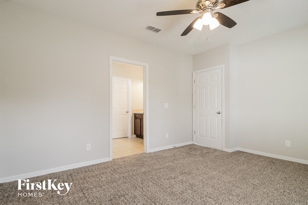 A spacious room with a carpeted floor and a ceiling fan.