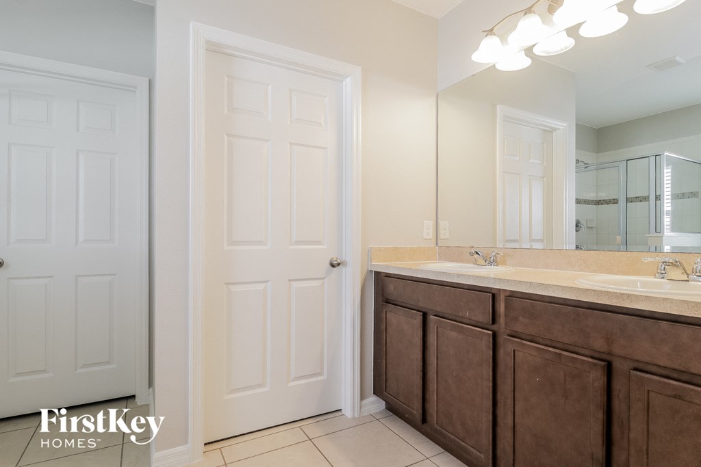 A bathroom with a white door and a brown vanity.