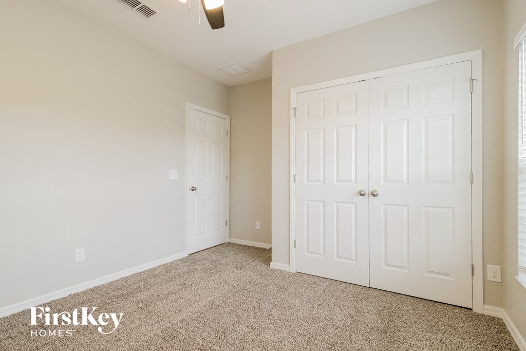 A room with a carpeted floor and two white doors.