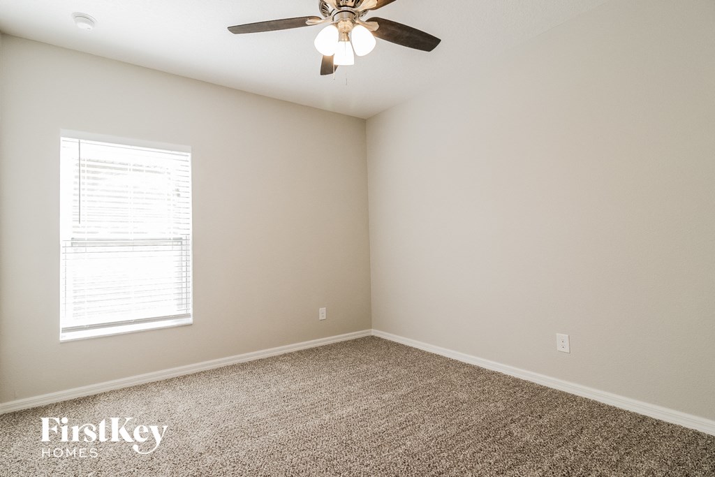 A room with a ceiling fan and a window with blinds.