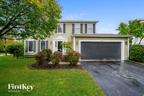 a yellow house with a driveway and a garage door