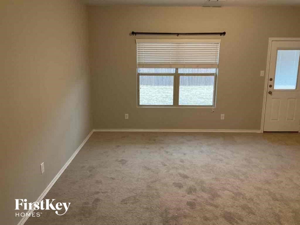 A room with a carpeted floor and a window with blinds.