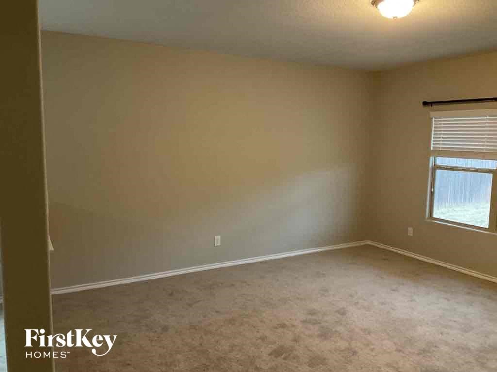 A room with a carpeted floor and a window with blinds.