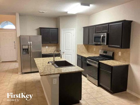 A kitchen with black cabinets and a granite countertop.