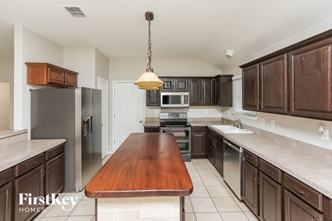 A kitchen with a wooden table and brown cabinets.