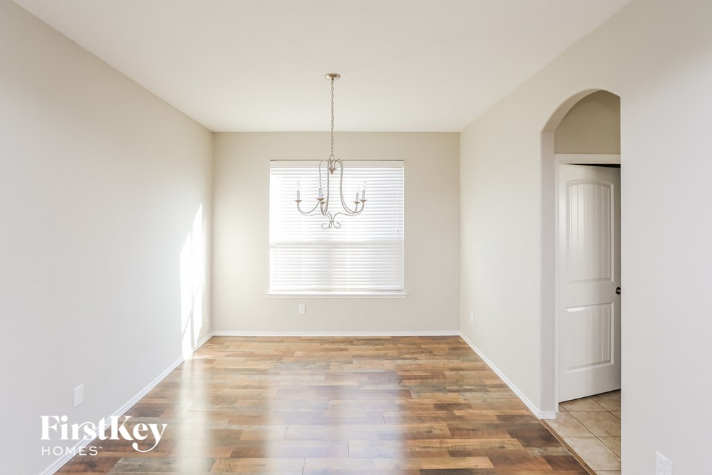 an empty living room with a door and a chandelier