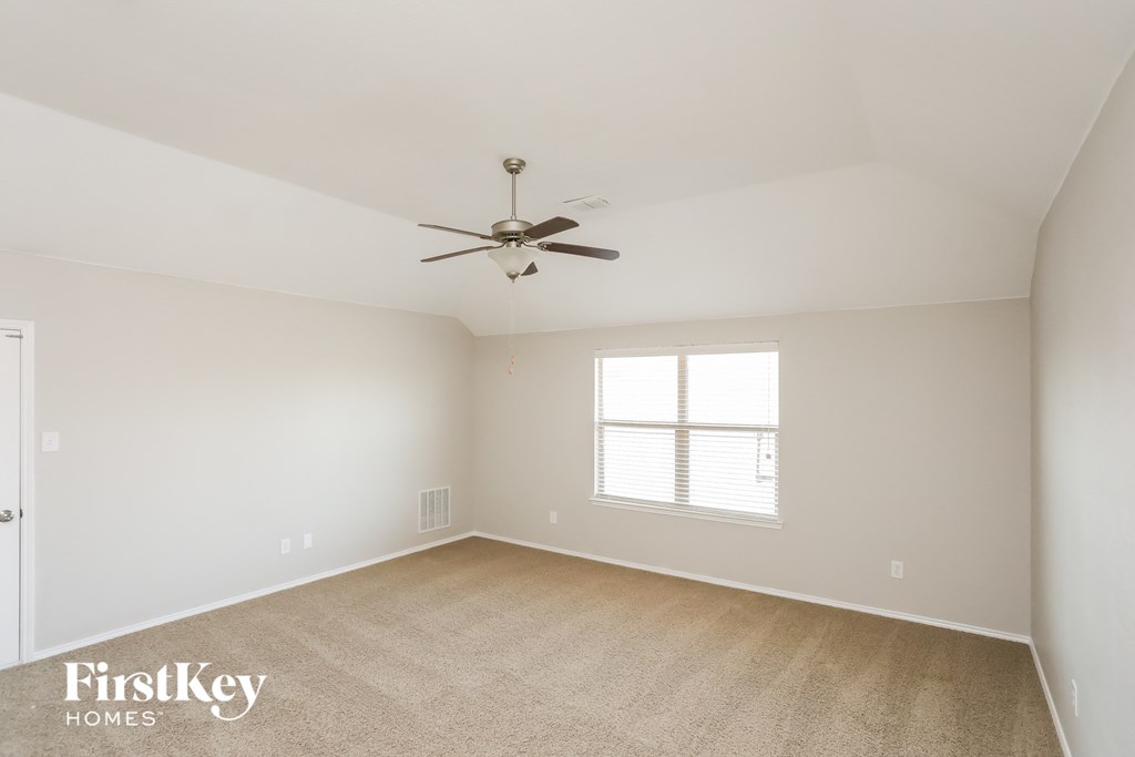 an empty room with a ceiling fan and a window